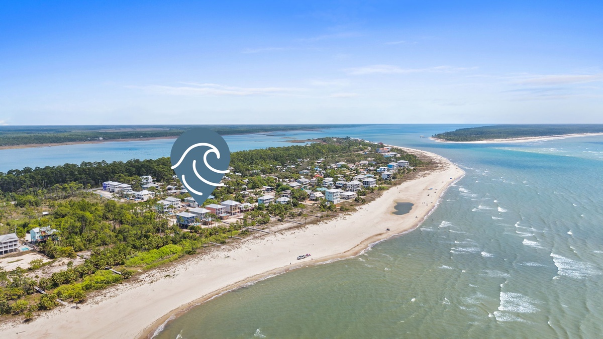 Stunning aerial view of pristine coastline with sandy beaches, turquoise waters, and charming coastal community nestled among lush greenery.