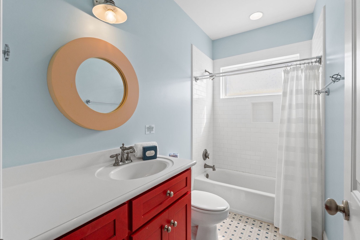 Freshen up in your bright, cheerful bathroom with calming blue walls, a vibrant red vanity, and a tub-shower combo perfect for unwinding after a day of adventure.