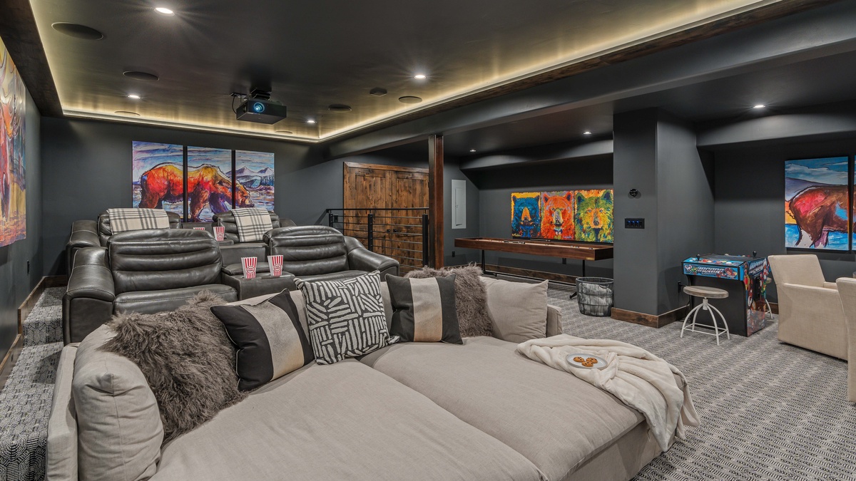 Theater room on lower level with a huge comfy couch, luxury theater seats, and shuffleboard, and arcade game