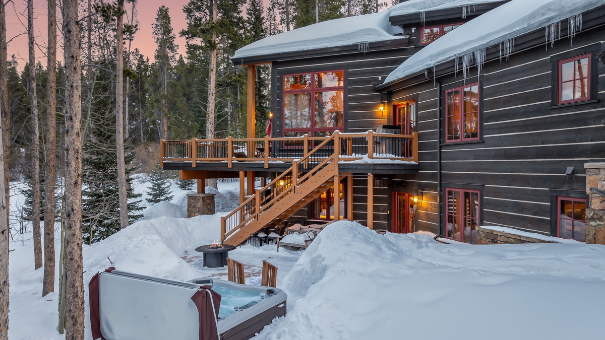 Aerial of the back patio area, with hot tub, fire pit, and stair access to main level deck