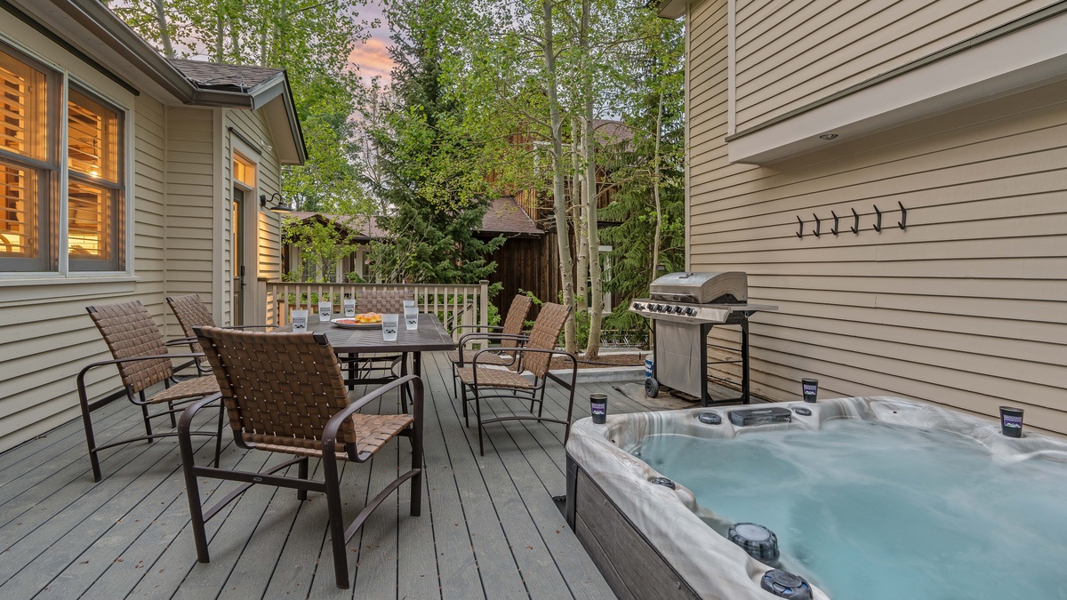 Private back deck with grill and hot tub connects the main house and carriage house
