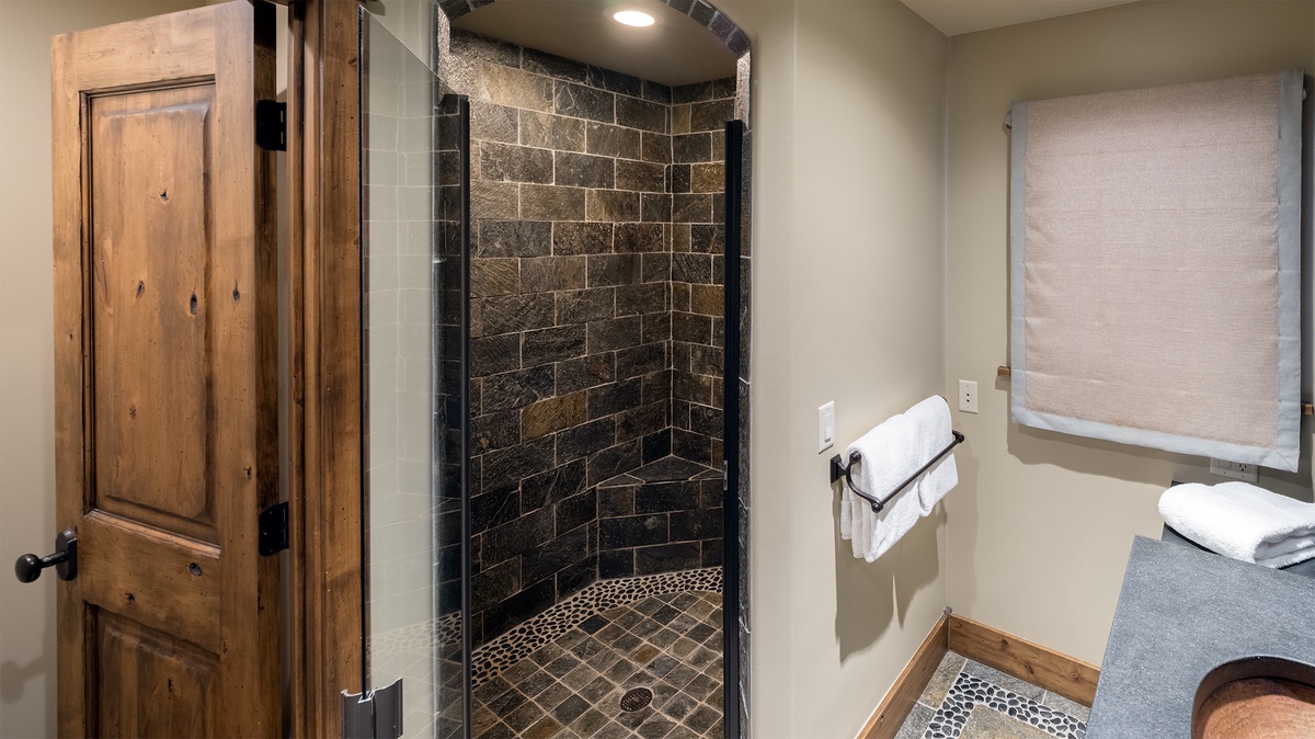 Step into this beautiful bathroom where natural stone tiles and modern glass create a spa-like retreat. Fresh towels await, and the earthy textures invite you to unwind after your day of adventure.