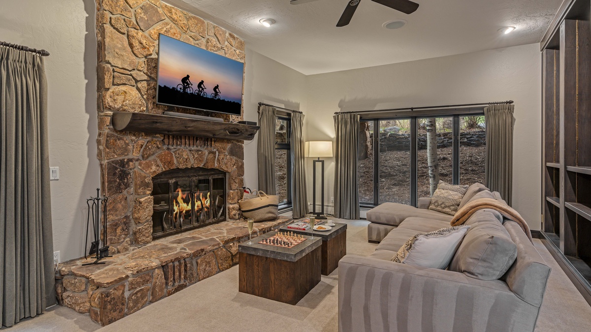 Sitting room of the guest apartment with wood fireplace, TV, and deck access; middle (3rd) level