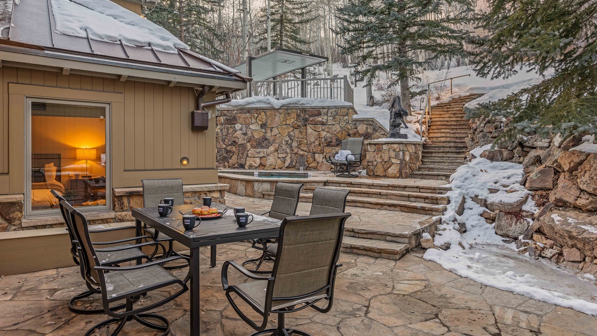 Back patio on main level with outdoor seating, private hot tub, grill, and stair access to ski-in/ski-out