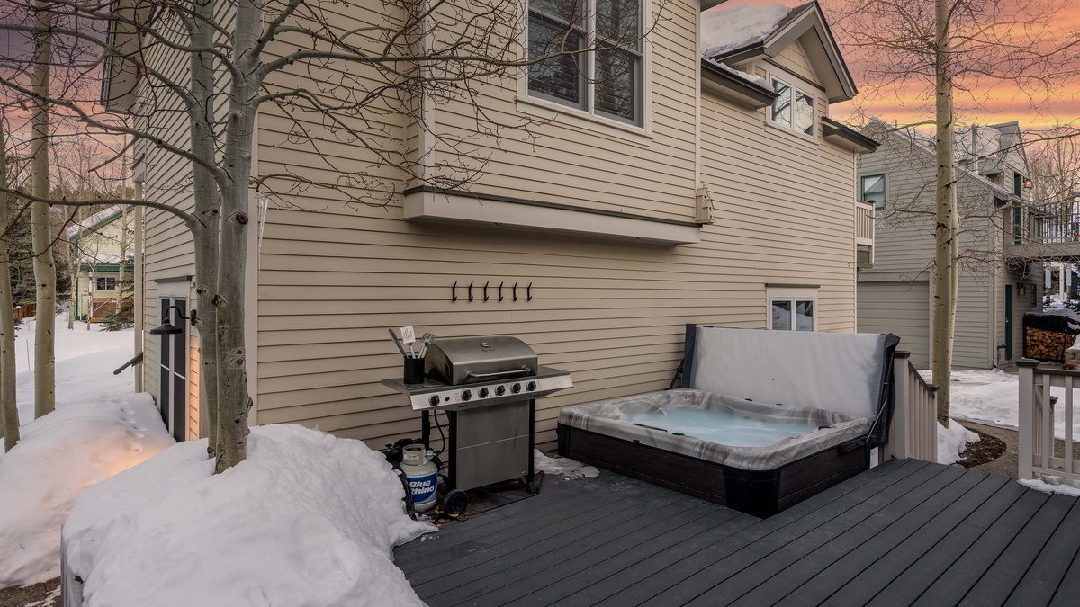 Private back deck with grill and hot tub connects the main house and carriage house