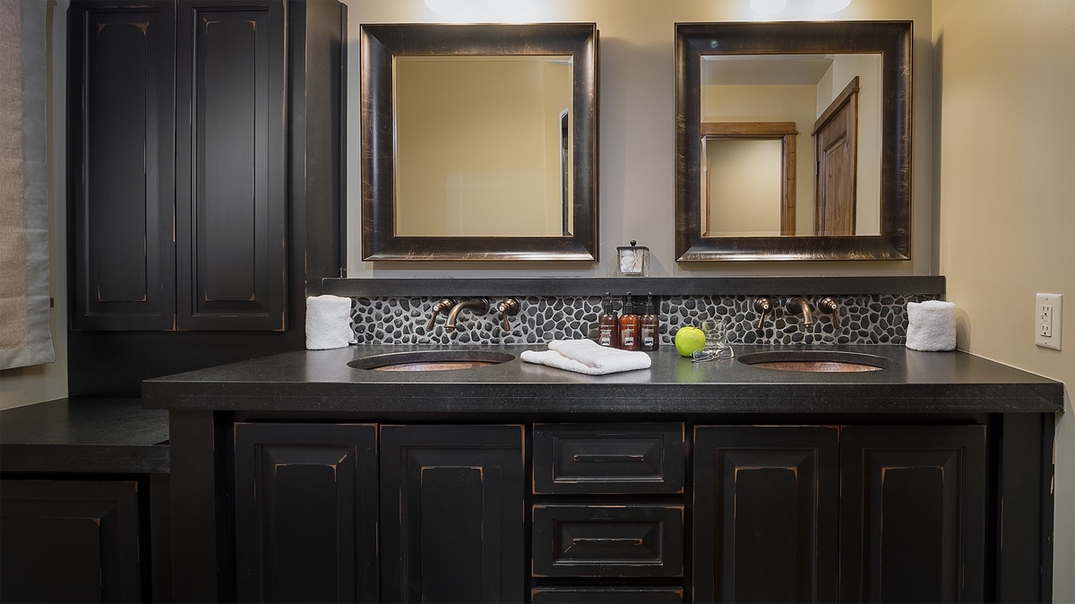 Unwind in your private spa-like bathroom with its sophisticated black cabinetry, dual vanities, and elegant pebble-tile backsplash. Fresh towels and premium amenities await your arrival.