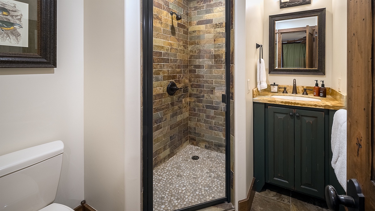Step into your private retreat with a beautifully tiled walk-in shower, elegant stone vanity, and warm rustic touches that blend comfort and style.