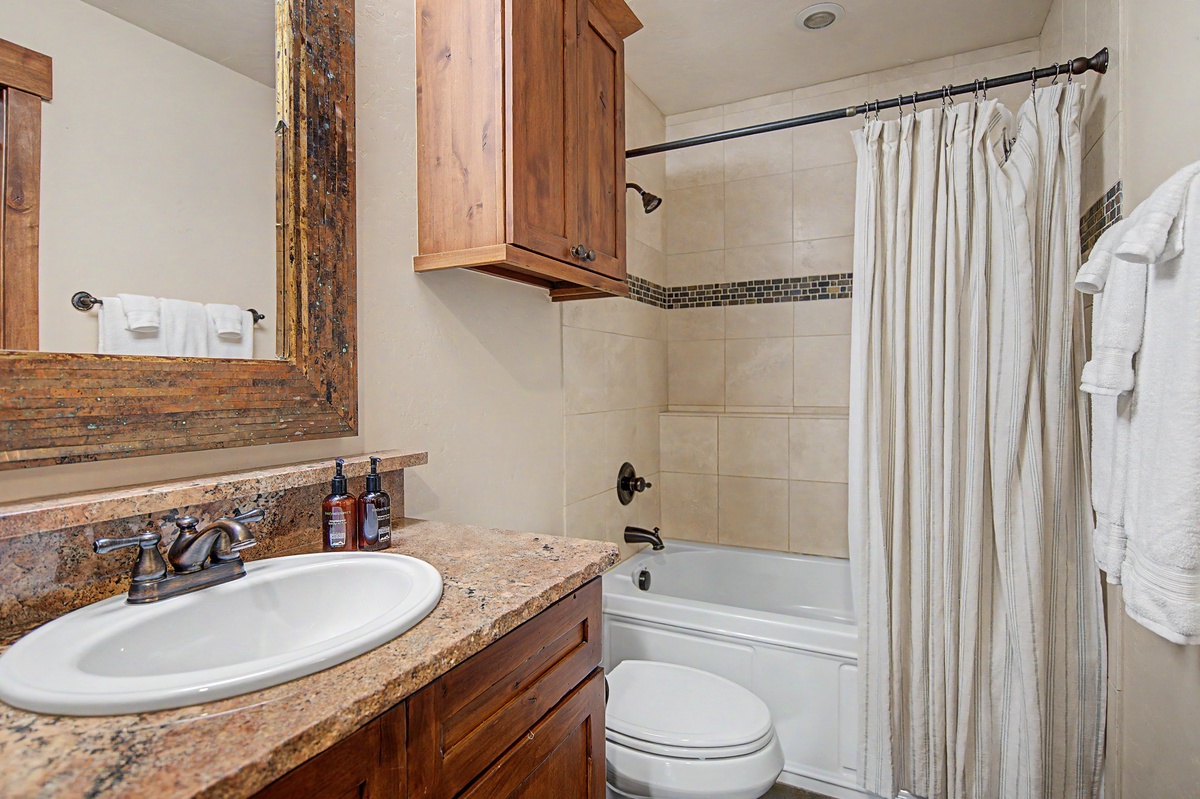 Shared Bathroom, Lower Level - Hall bathroom adjacent to Bedroom 2 with single vanity and shower/tub combo