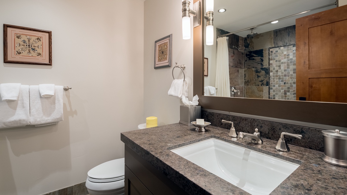 Your beautifully appointed bathroom features elegant granite countertops, a spacious walk-in shower with mosaic tile, and plush white towels ready for your arrival.