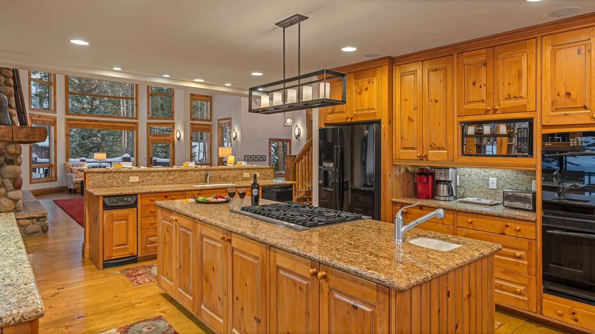 Kitchen features double ovens, gas cooktop, two sinks, and breakfast bar seating