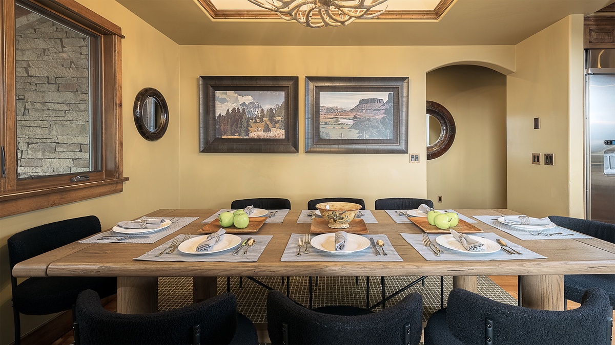 Gather around this inviting dining table set for shared meals and memories, beneath a stunning ceiling detail and warm western artwork that makes every dinner feel special.