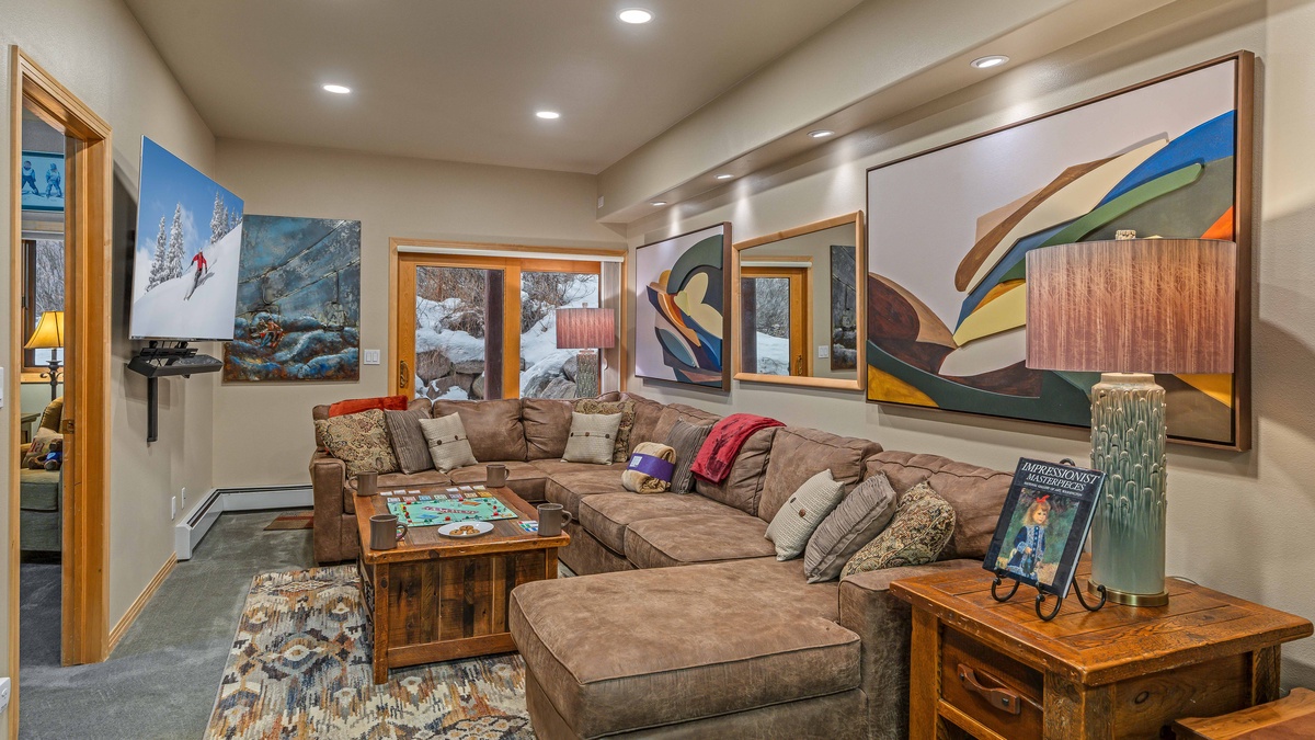 Lower family room with large couch and TV