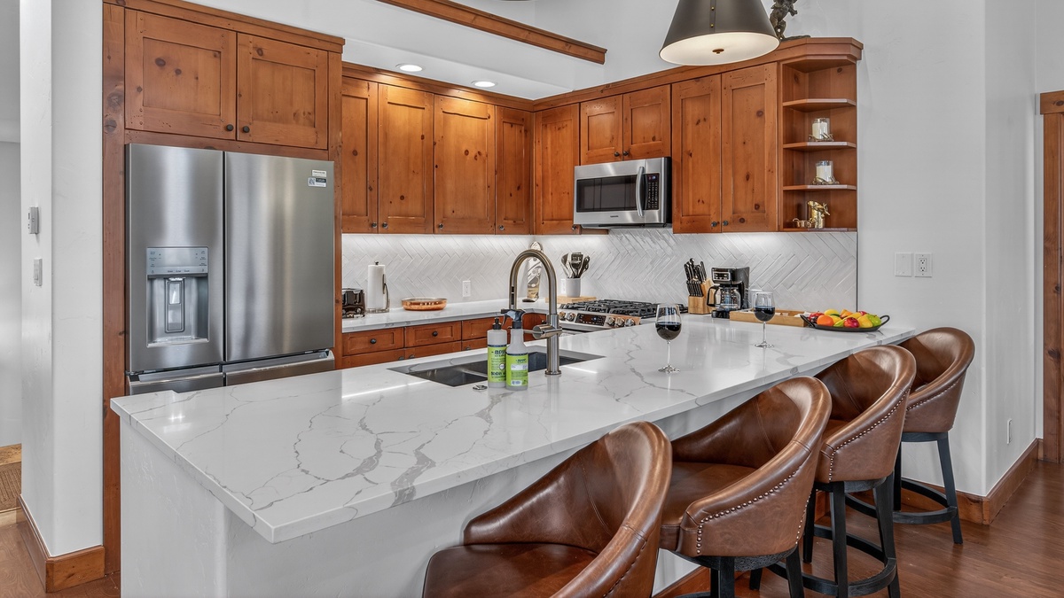 Your gourmet kitchen awaits with rich wood cabinetry, marble island, and premium appliances perfect for creating memorable meals together.