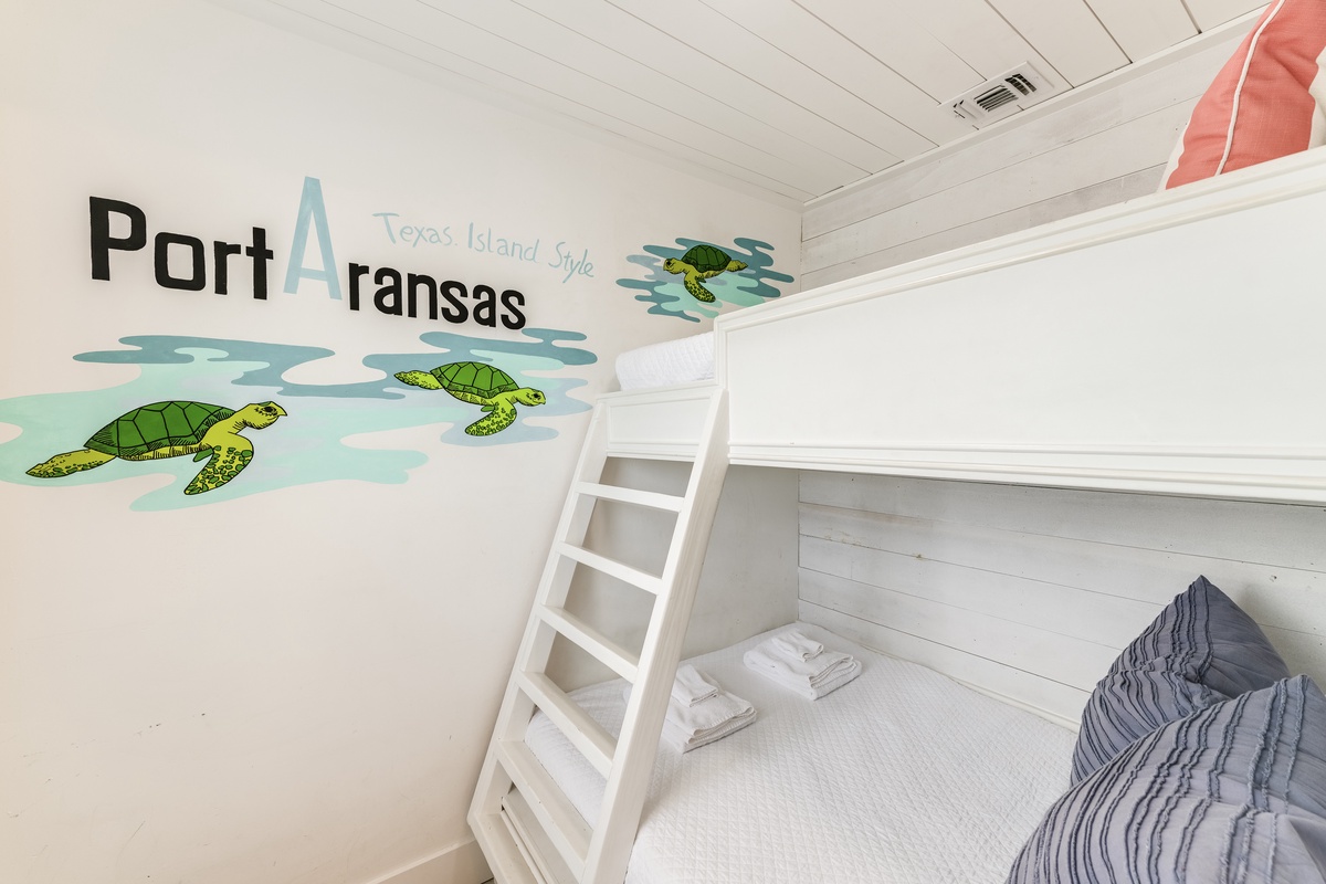 Relax in your cozy bunk room adorned with playful sea turtle murals and a bright, beachy vibe that captures the spirit of Port Aransas.