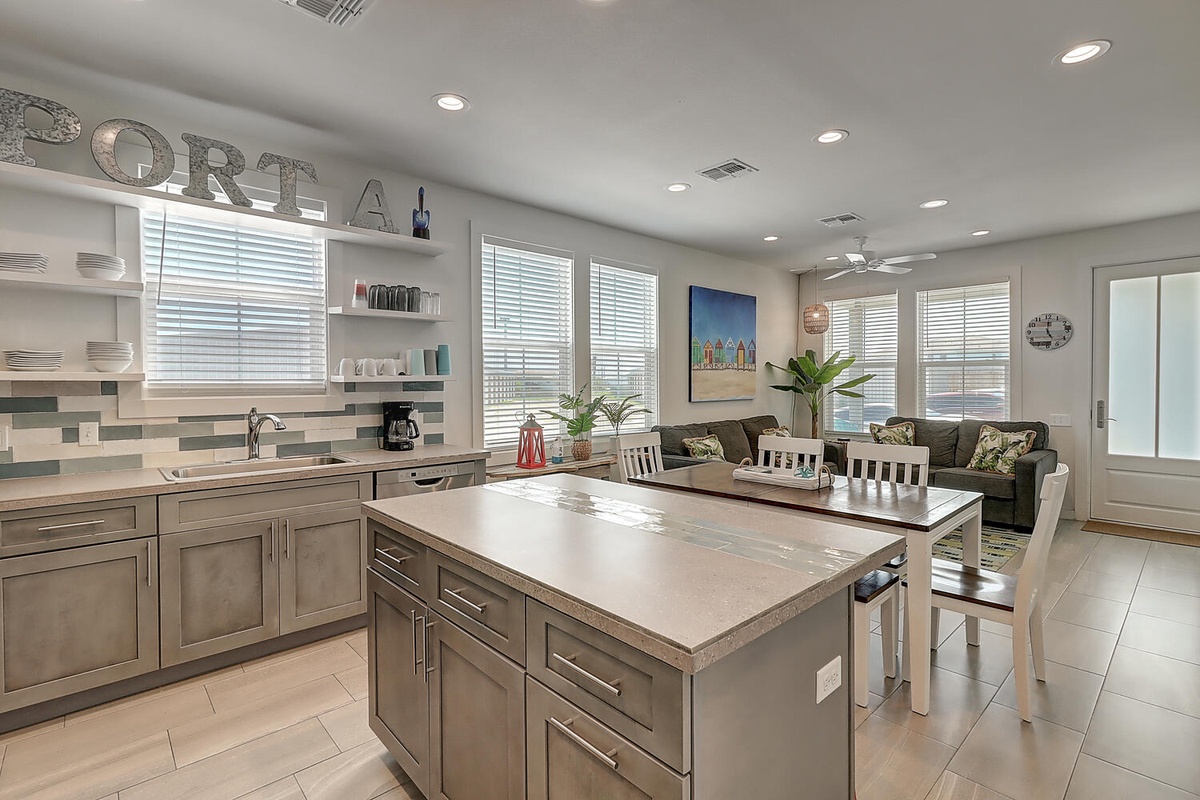 Your open-concept kitchen flows seamlessly into the living space, featuring modern appliances, elegant island seating, and coastal charm throughout.