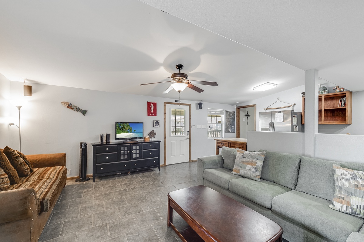 Relax in your spacious living room with comfortable seating, entertainment center, and ceiling fan creating the perfect atmosphere for unwinding.