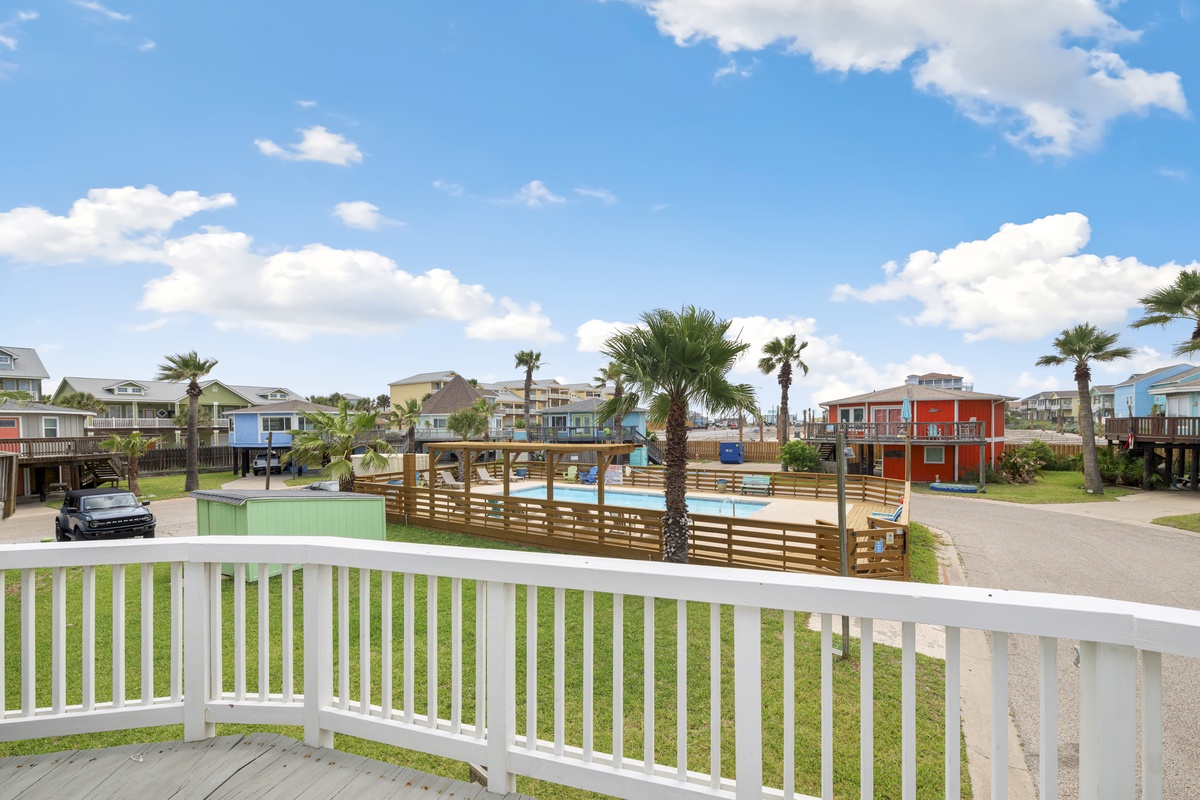 Colorful beach houses and community pool create a vibrant coastal neighborhood under bright blue skies.