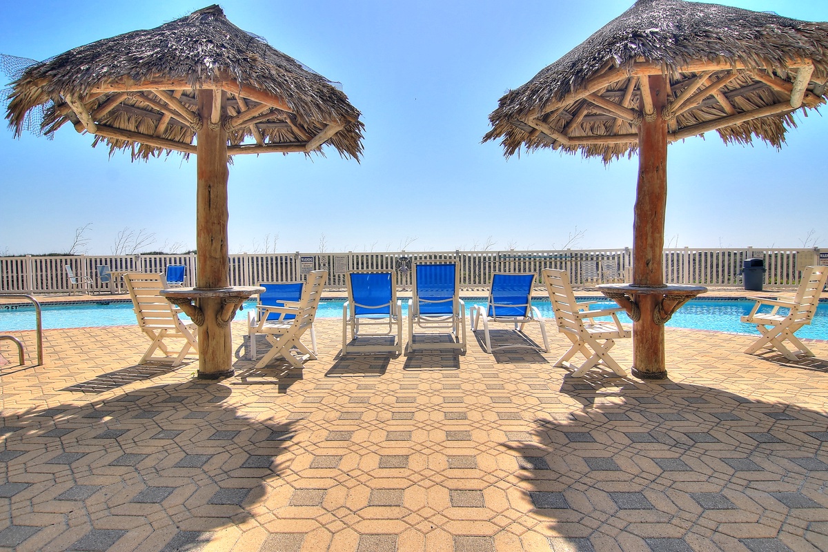 Relax under tropical thatched umbrellas by the sparkling pool, where comfortable lounge chairs await your perfect sunny afternoon.