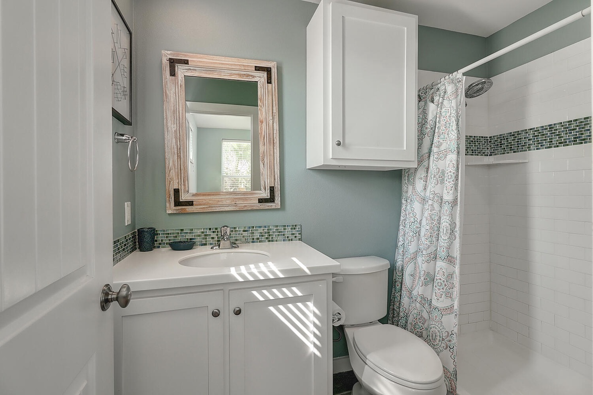 Step into your private bathroom with calming sea-foam walls, elegant mosaic tile accents, and plenty of natural light streaming in.