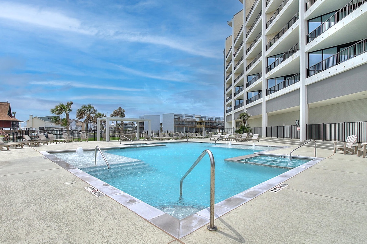 Modern beachfront property featuring a pristine outdoor swimming pool with convenient hot tub access and comfortable poolside lounging areas.