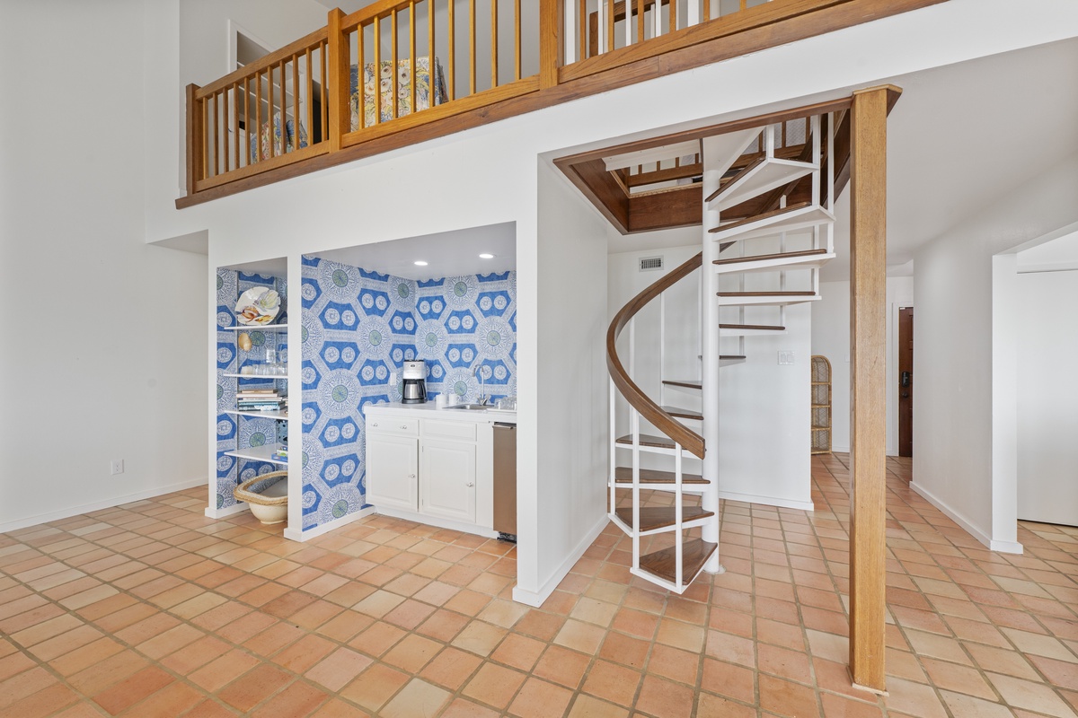 Relax in your charming loft with spiral staircase, cheerful blue-tiled kitchen nook, and warm terracotta floors throughout.