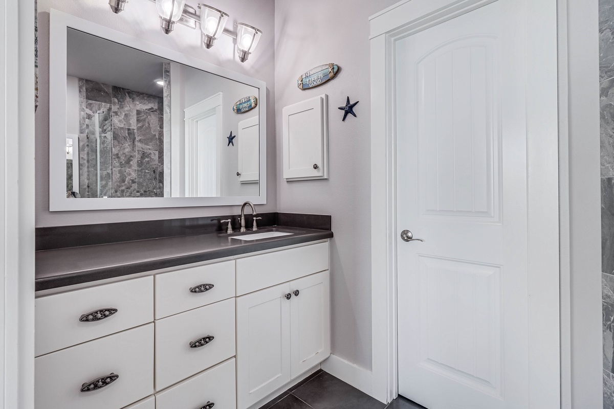 Your beautifully appointed bathroom features elegant white cabinetry, sleek granite countertops, and charming nautical touches that create a fresh, coastal retreat.