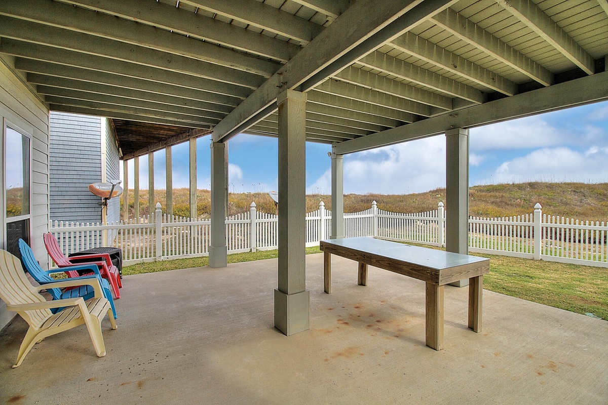 Relax under your covered patio while enjoying coastal views. This spacious outdoor area features comfortable seating and a large table for dining.