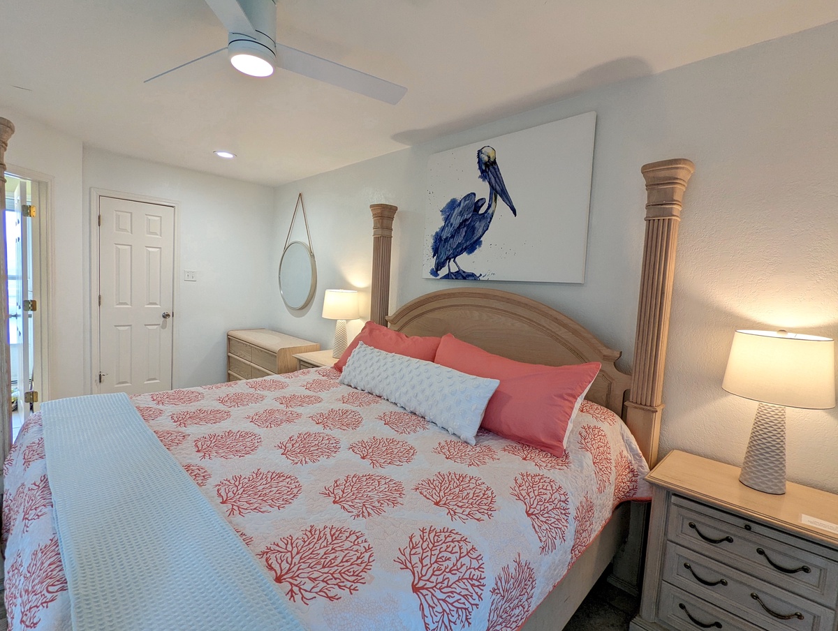 Sleep peacefully in your coastal-themed bedroom with coral bedding and pelican artwork creating a serene beach atmosphere.