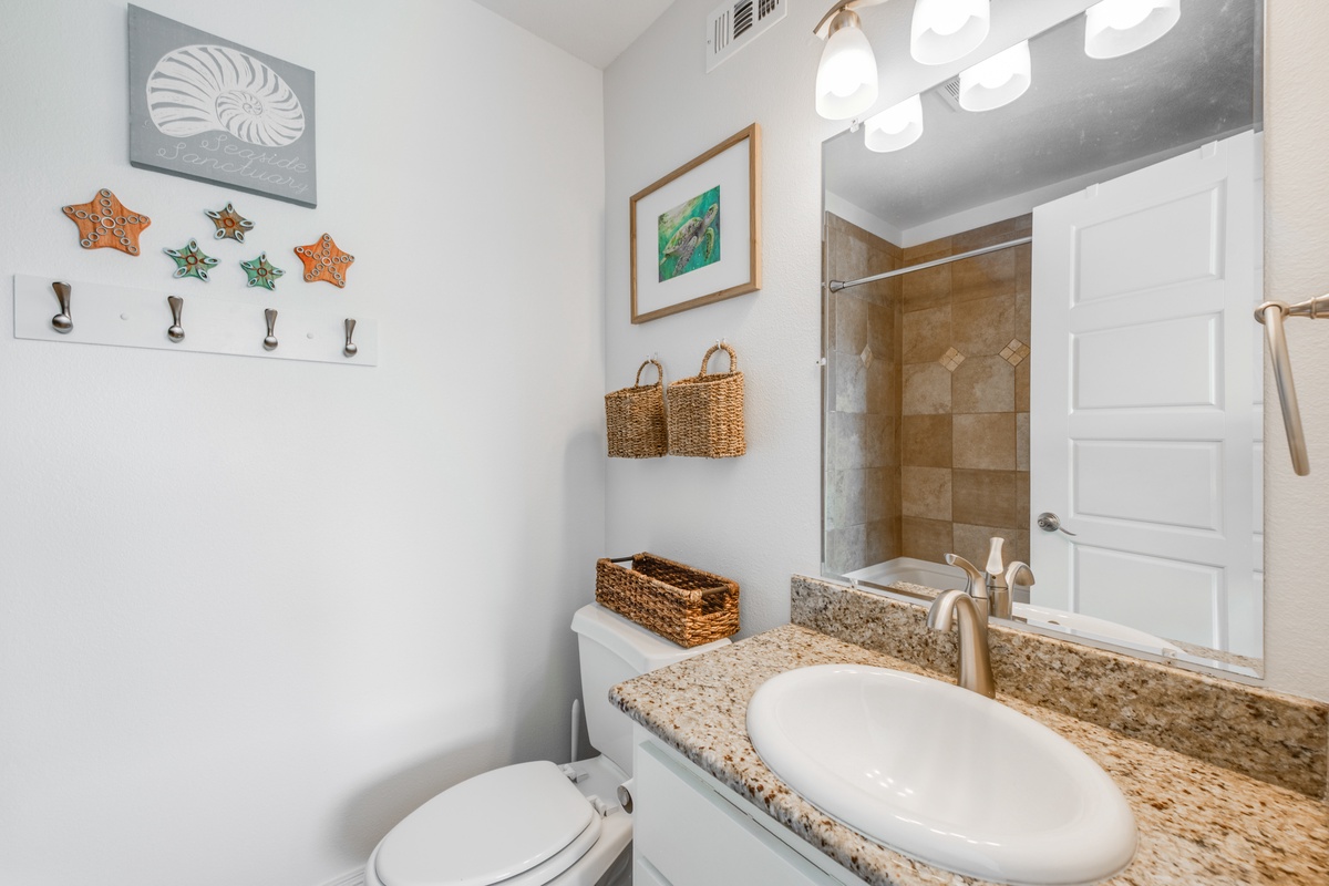 Freshen up in your charming coastal-themed bathroom with granite counters, thoughtful storage, and a spacious walk-in shower.