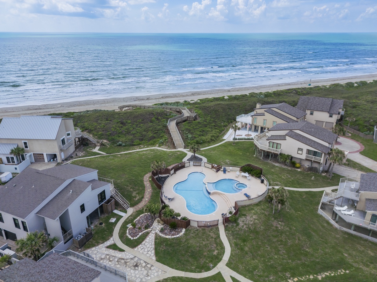 Coastal community with ocean access, curved pool, and beachfront boardwalk connecting to pristine sandy shores.