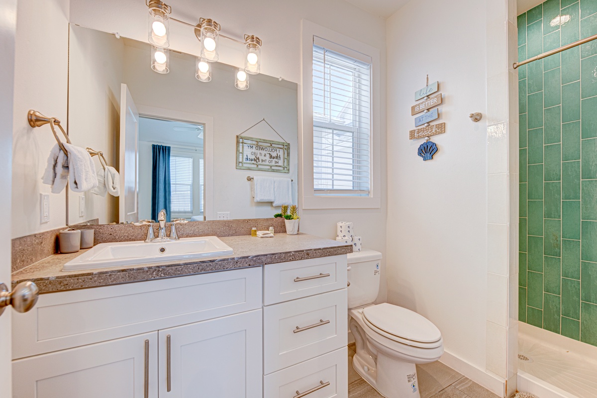Step into your bright bathroom featuring sea-glass tiled shower and coastal charm touches throughout.
