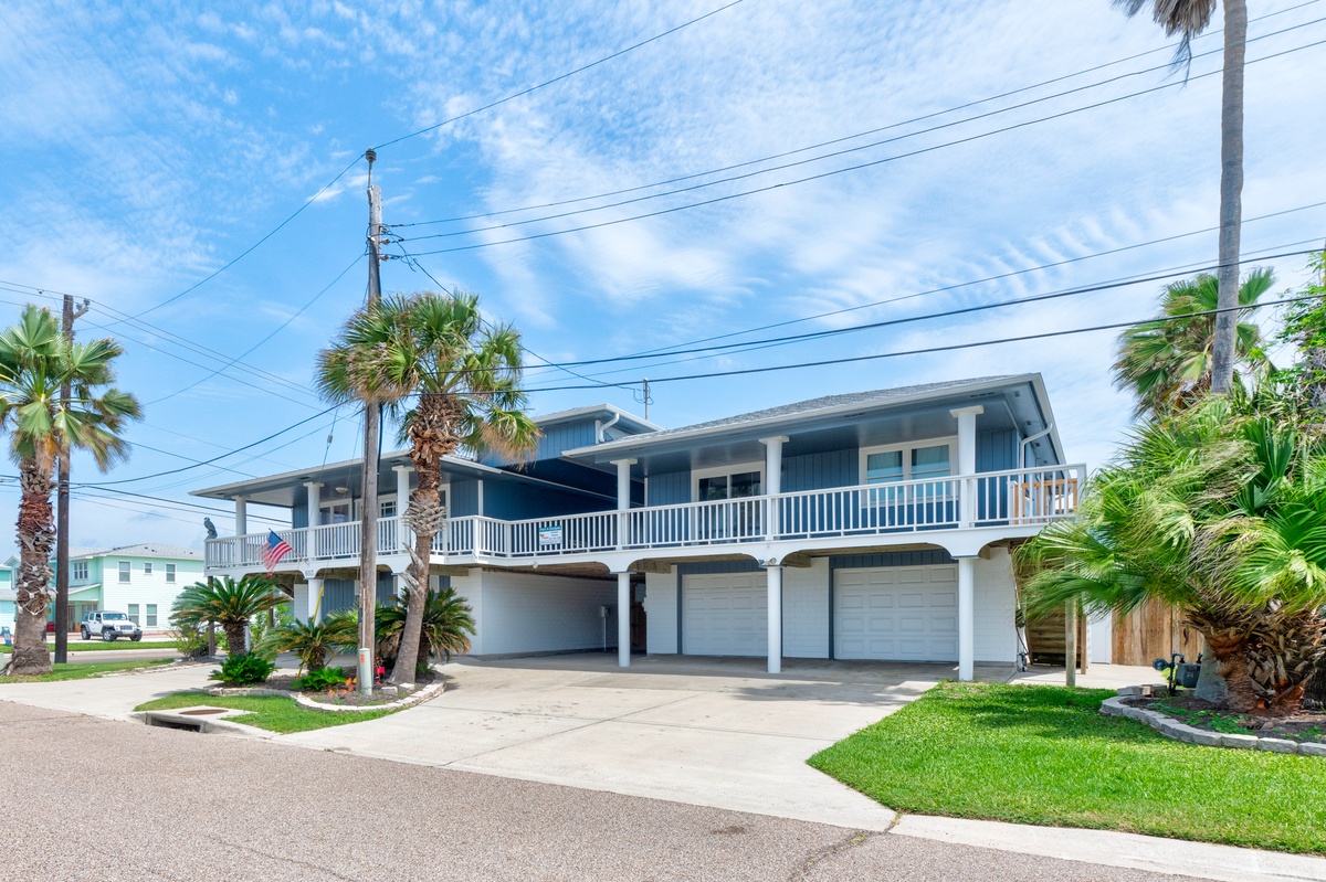 Coastal vacation home with tropical palm trees and spacious garage parking in a quiet residential neighborhood.