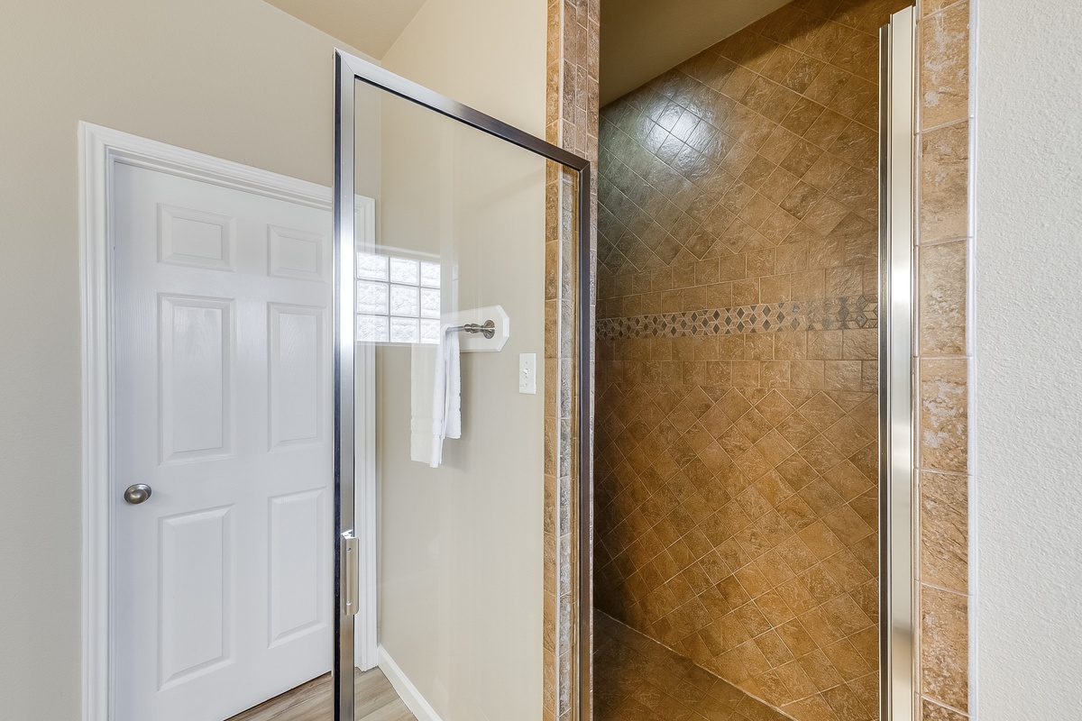 Step into your private spa-like shower with beautiful stone tiles and glass enclosure for a refreshing retreat.