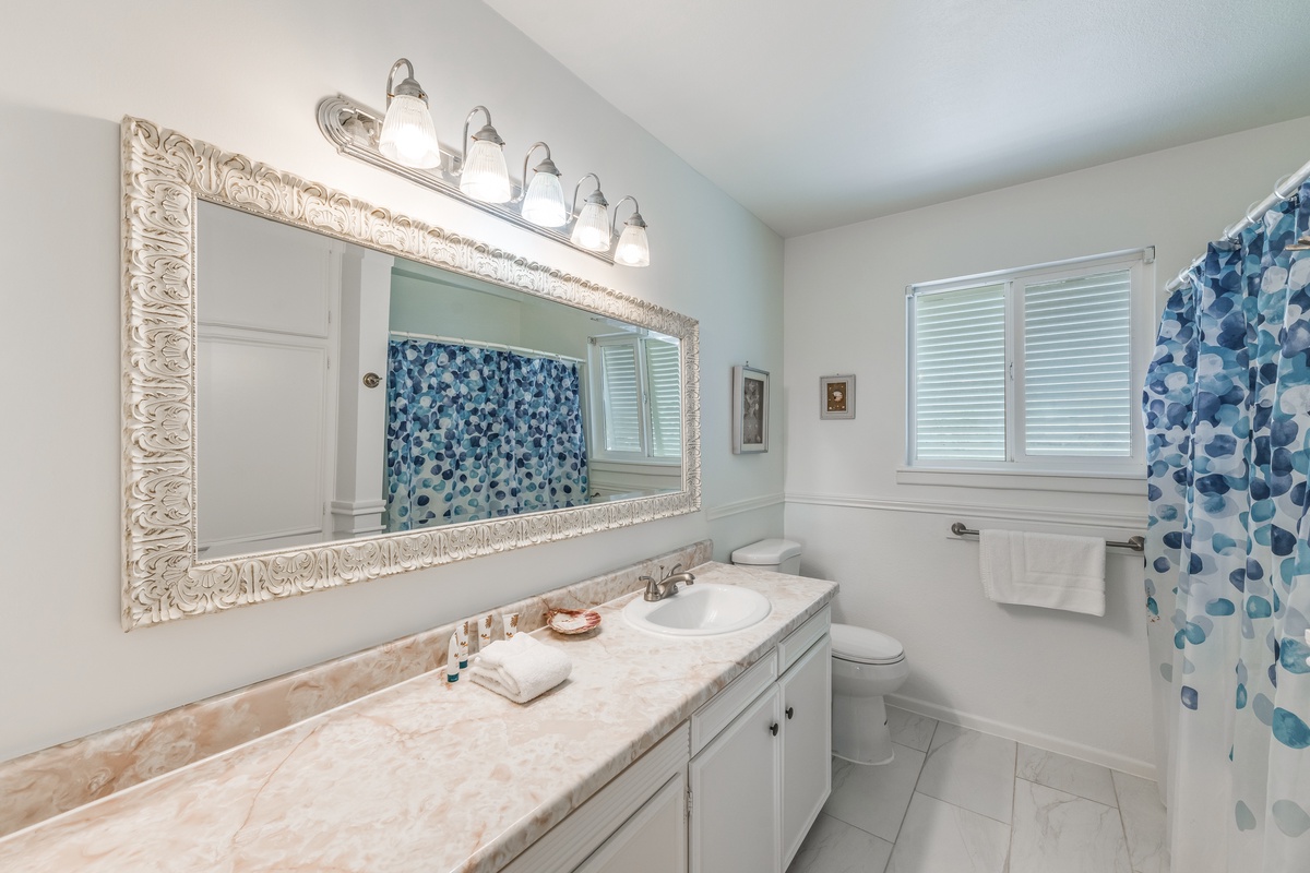 Your elegant bathroom features marble countertops, ornate framing, and bright vanity lighting for your morning routine.