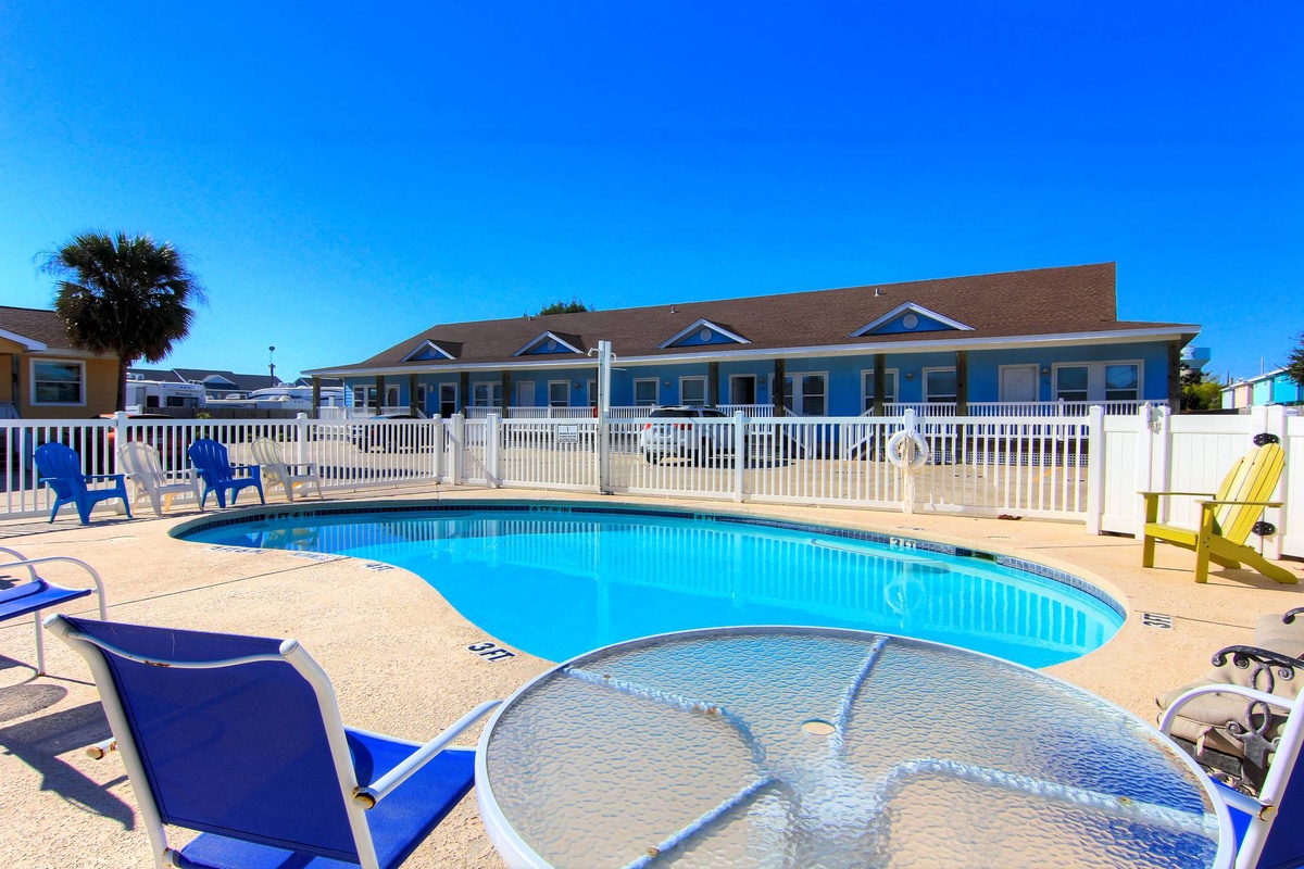 Bright blue pool and bubbling spa await your relaxation, surrounded by cheerful chairs and sunny skies.