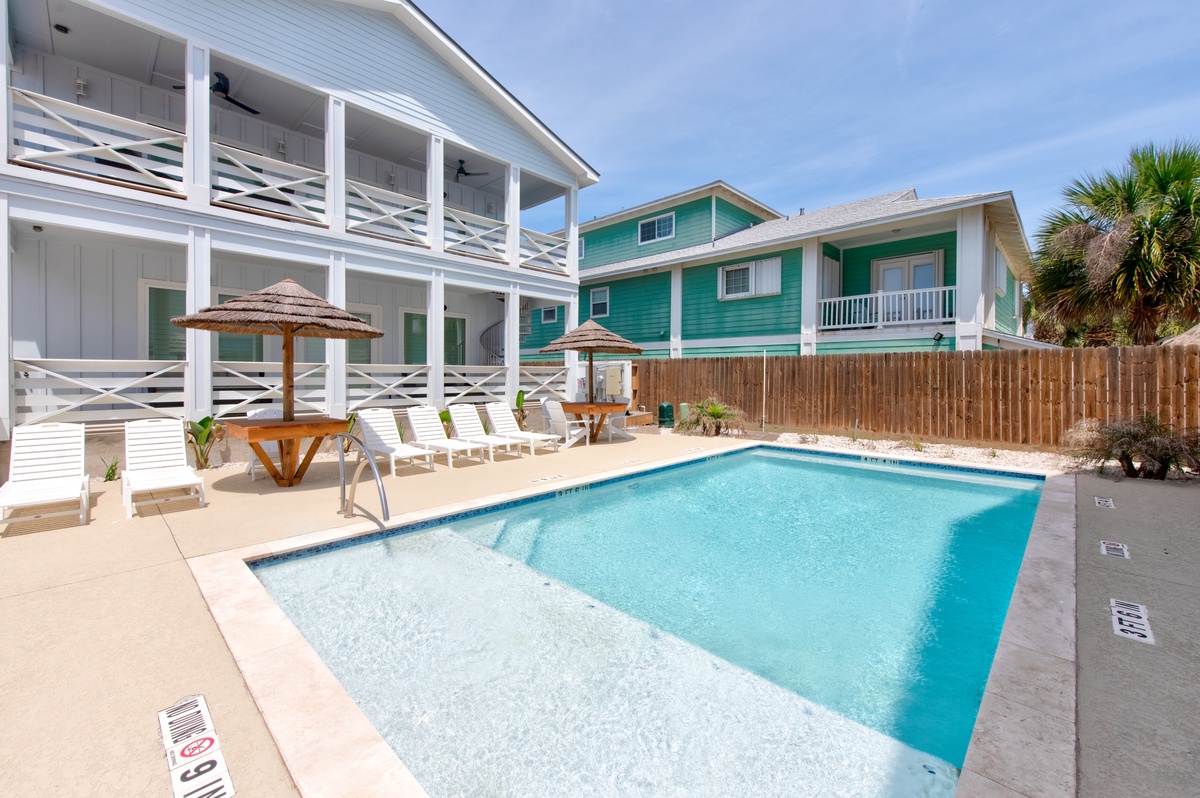 Community pool oasis awaits with sparkling blue water, poolside loungers, and shaded umbrellas for ultimate relaxation.