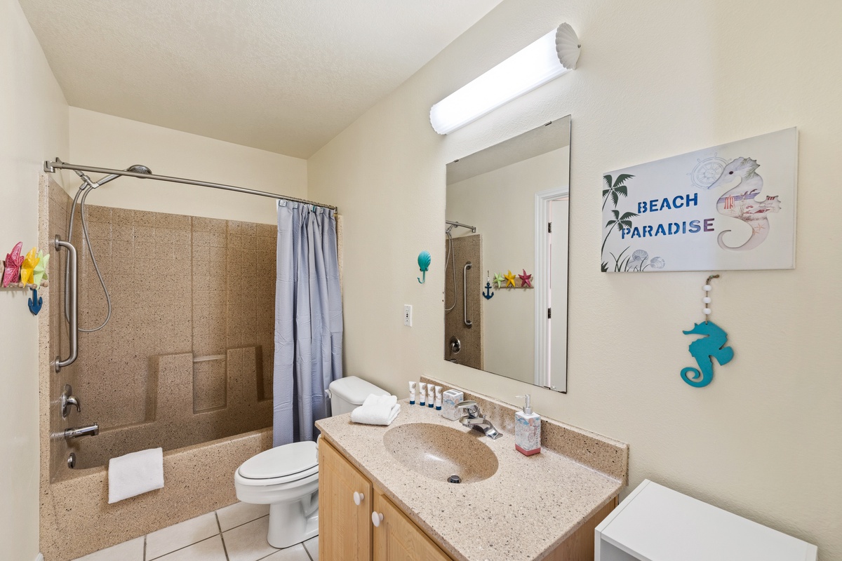 Your private bathroom features a full tub-shower combination, fresh towels, and thoughtful beach-themed touches to help you feel right at home during your stay.