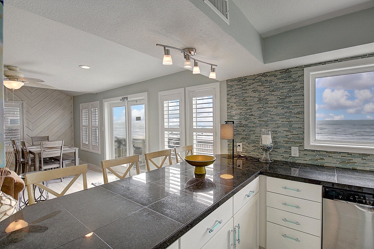 Your bright kitchen flows seamlessly into the dining space, where sleek granite counters and coastal tile create a sophisticated backdrop for memorable meals together.