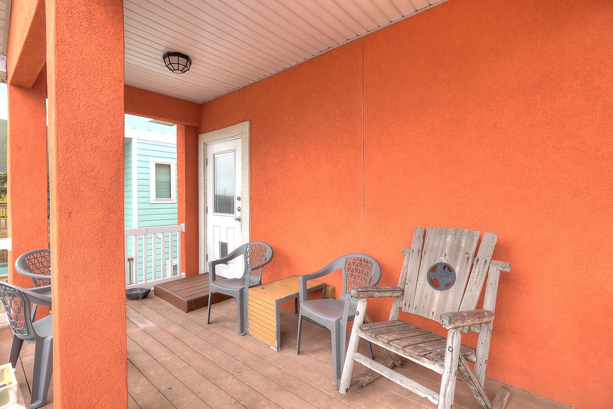 Your covered porch offers a perfect morning coffee spot with comfortable seating and vibrant coral walls that catch the warm light.