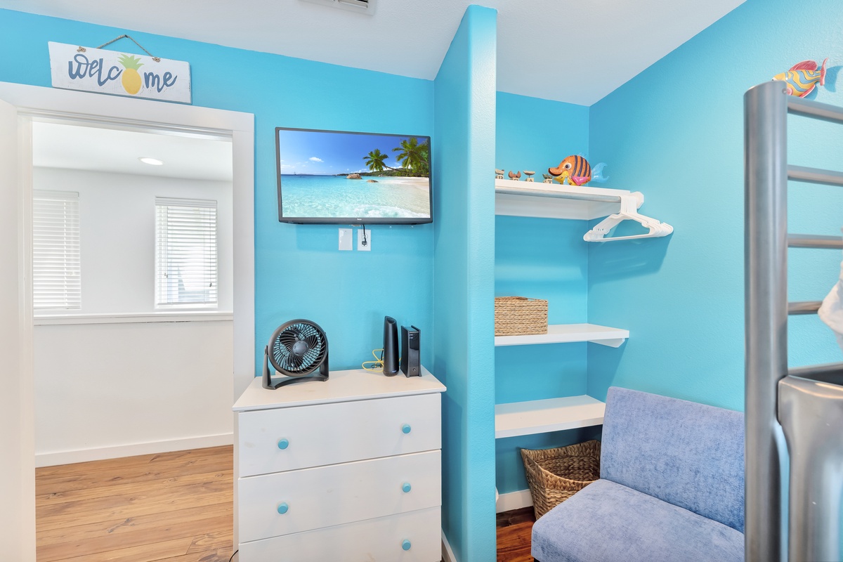Relax in your bright beach-themed retreat with turquoise walls, tropical TV scenery, and cozy seating for peaceful moments.