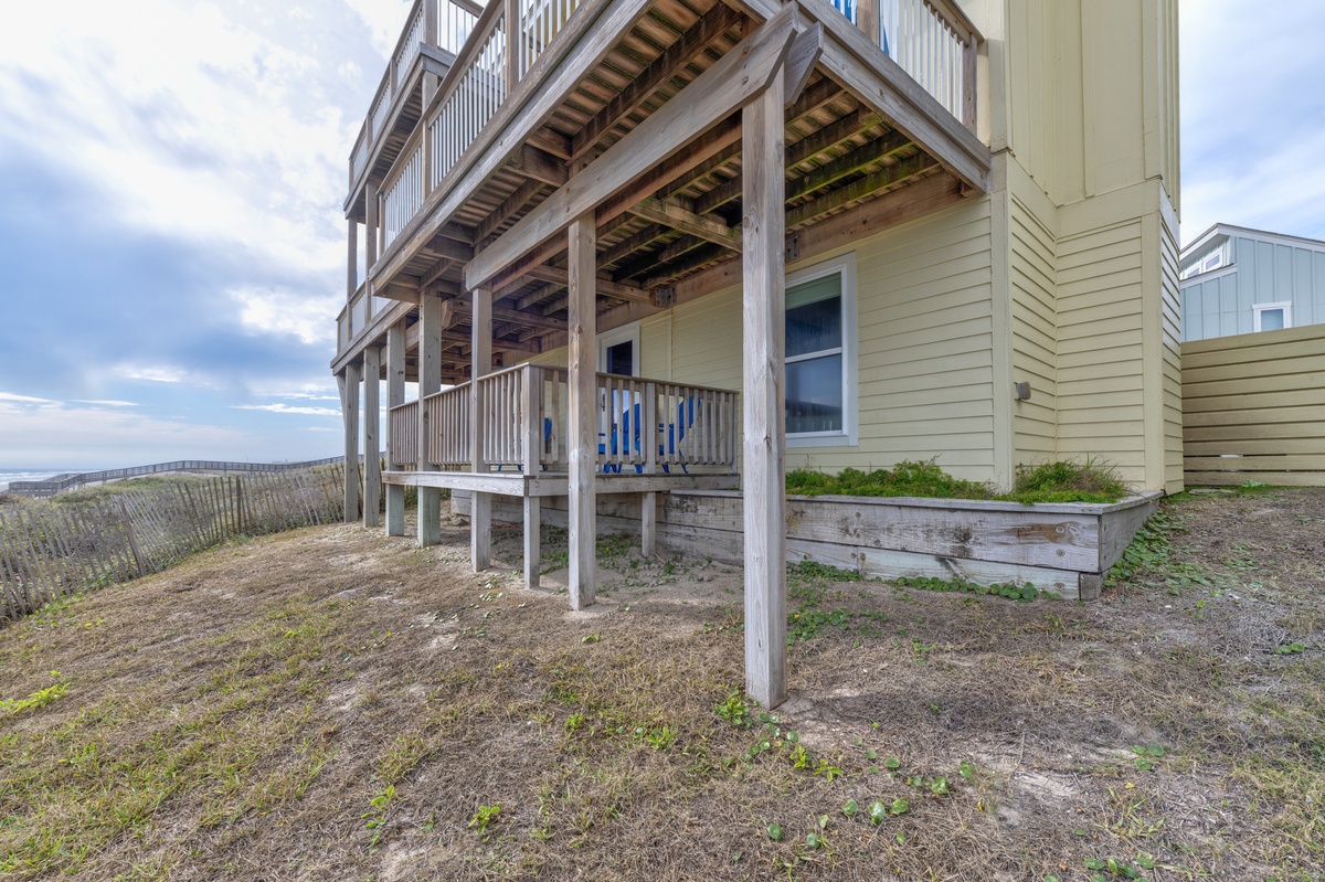 Coastal property featuring multi-level wooden decking and beach access with oceanfront views nearby.