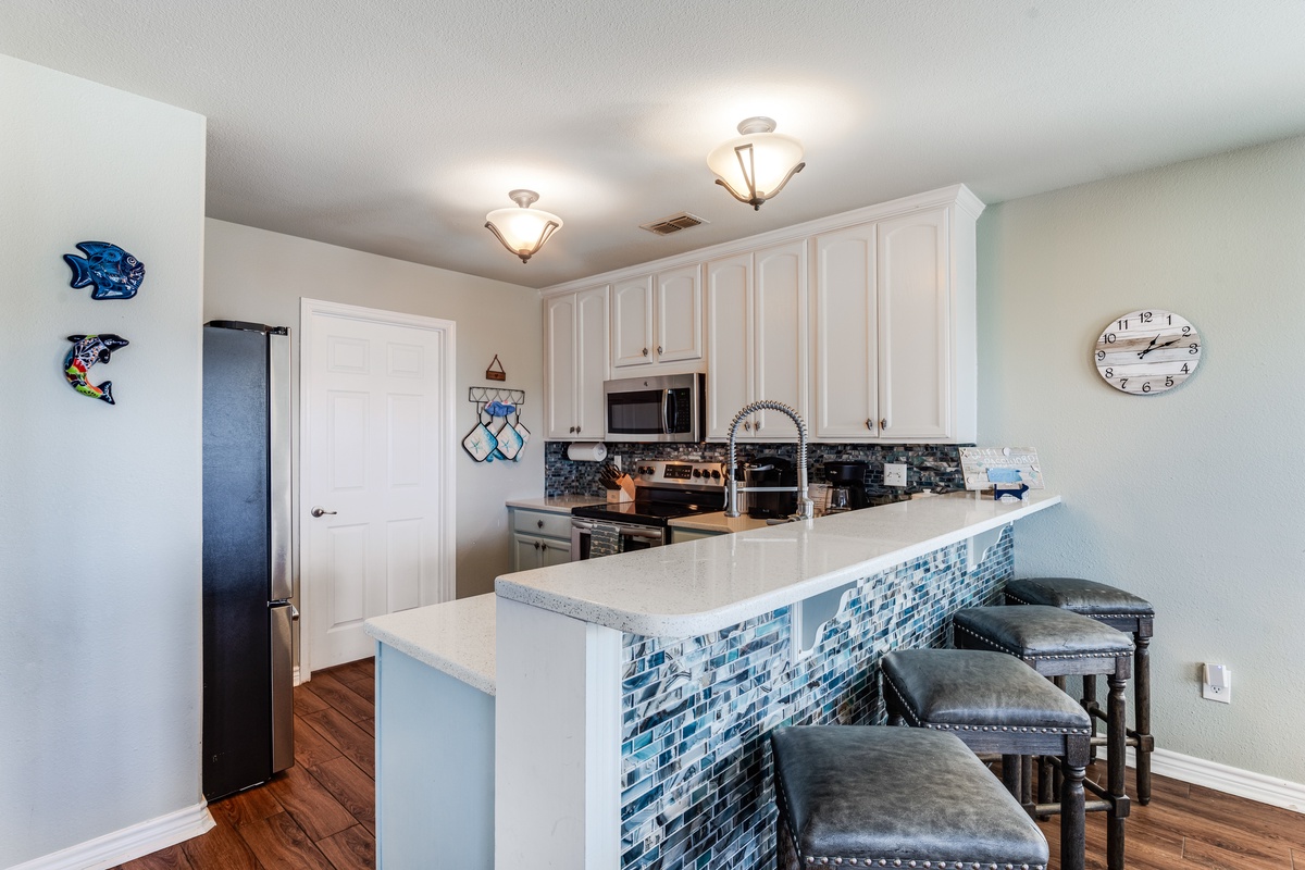 Your stylish kitchen features white cabinets, stunning blue mosaic tile work, and a breakfast bar perfect for morning coffee.