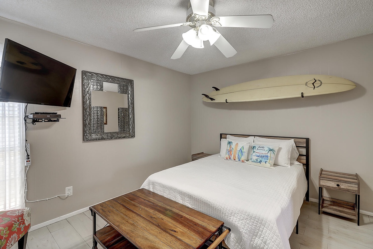 Your coastal retreat awaits with a surfboard above your bed and TV for cozy nights after beach adventures.