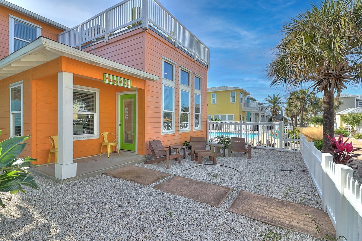 Bright coastal property featuring vibrant orange exterior with tropical landscaping and multiple colorful buildings in a beach community setting.