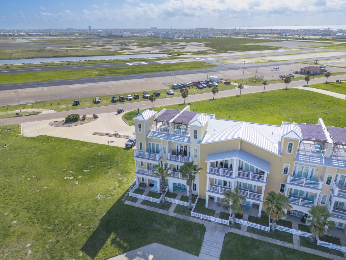 Modern beachfront property with multiple balconies overlooking expansive green spaces and distant airport runways.