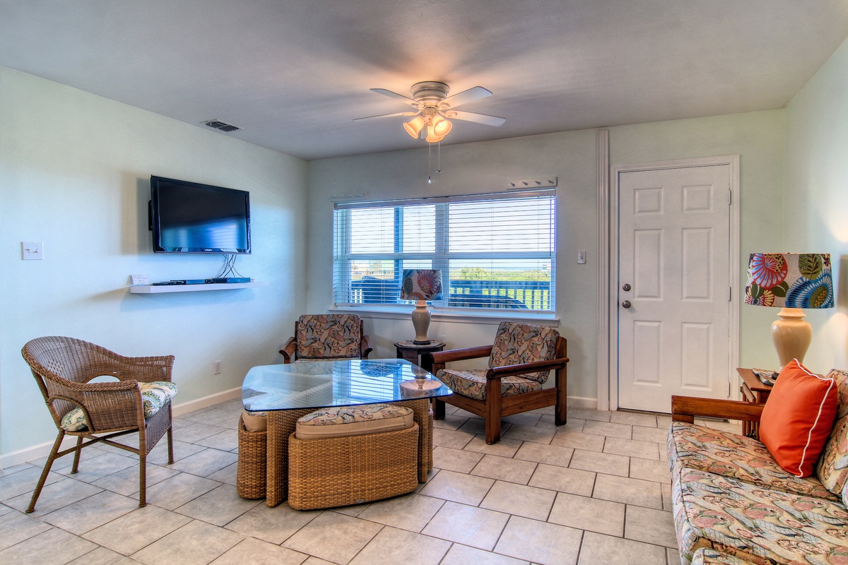 Unwind in your bright living room with tropical décor, ceiling fan, and TV—perfect for relaxing after beach days.