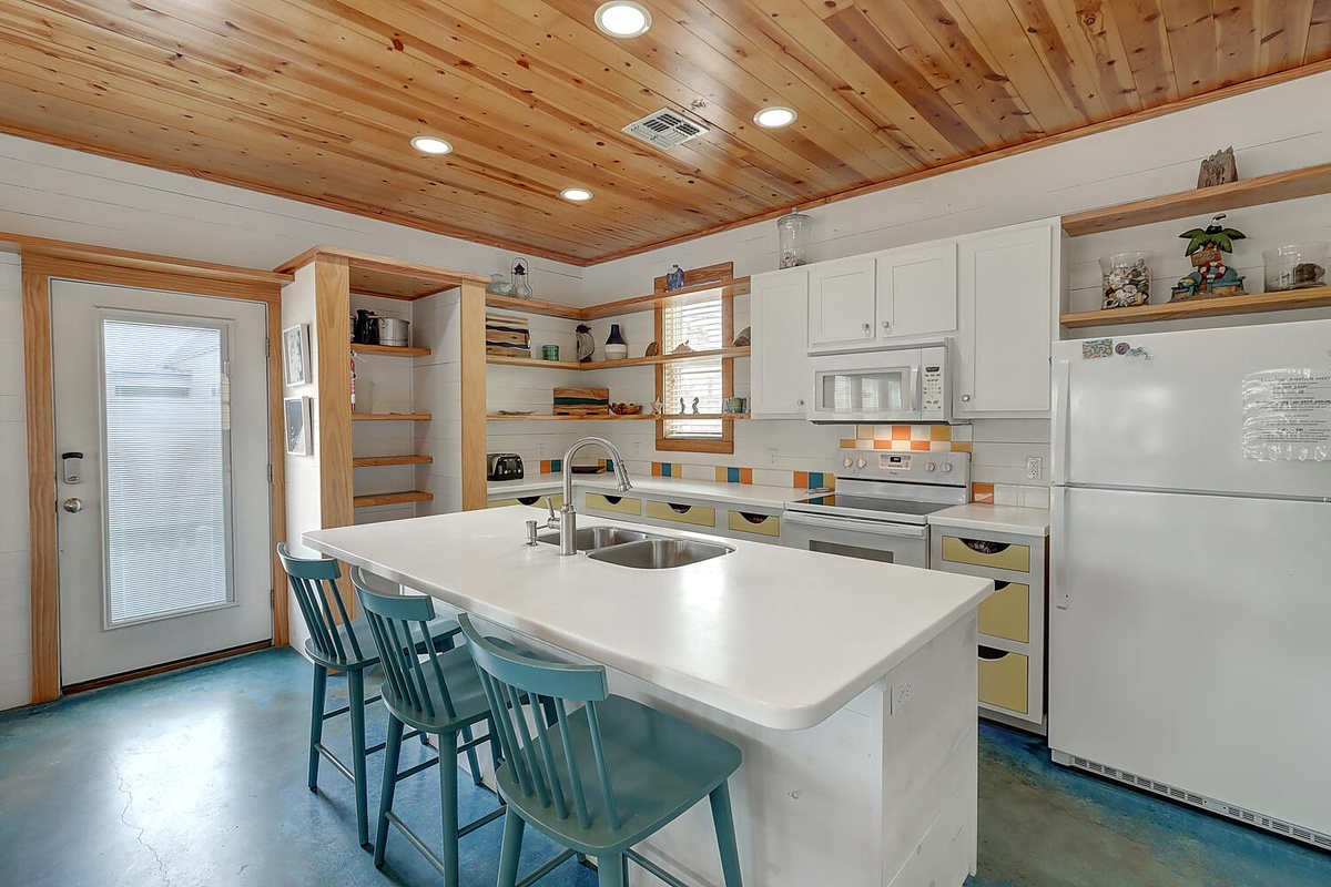 Your fully-equipped kitchen invites culinary adventures with its spacious island, modern appliances, and warm wood ceiling creating a welcoming atmosphere.