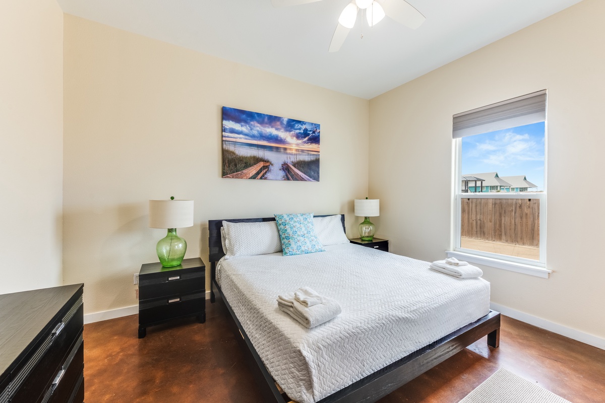 Sink into your comfortable queen bed and wake to natural light streaming through your window, with coastal artwork setting a peaceful mood.