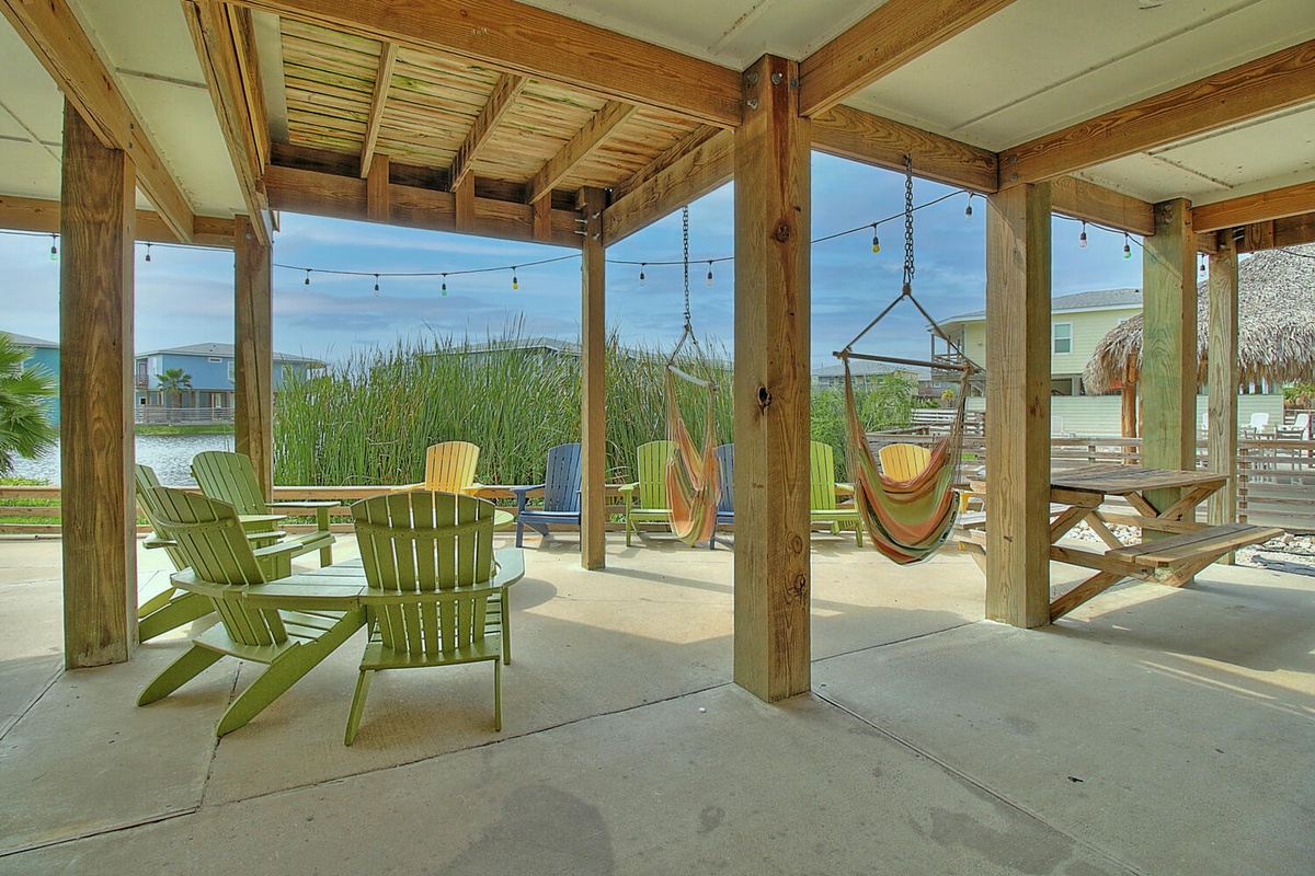 Unwind in your covered patio with colorful Adirondack chairs and a swaying hammock, where coastal breezes and twinkling string lights create pure relaxation.
