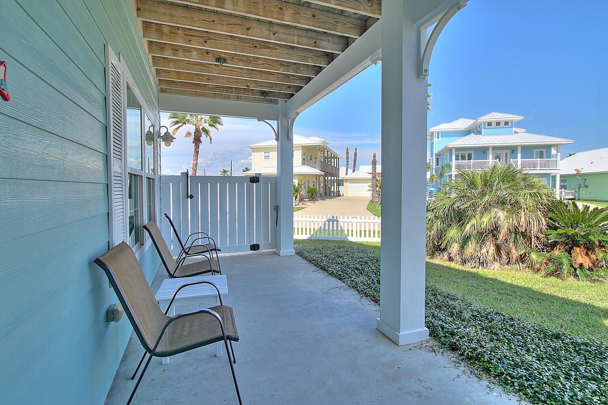 Relax on your covered porch with comfortable seating while enjoying tropical palm views and colorful beachside neighborhood charm.